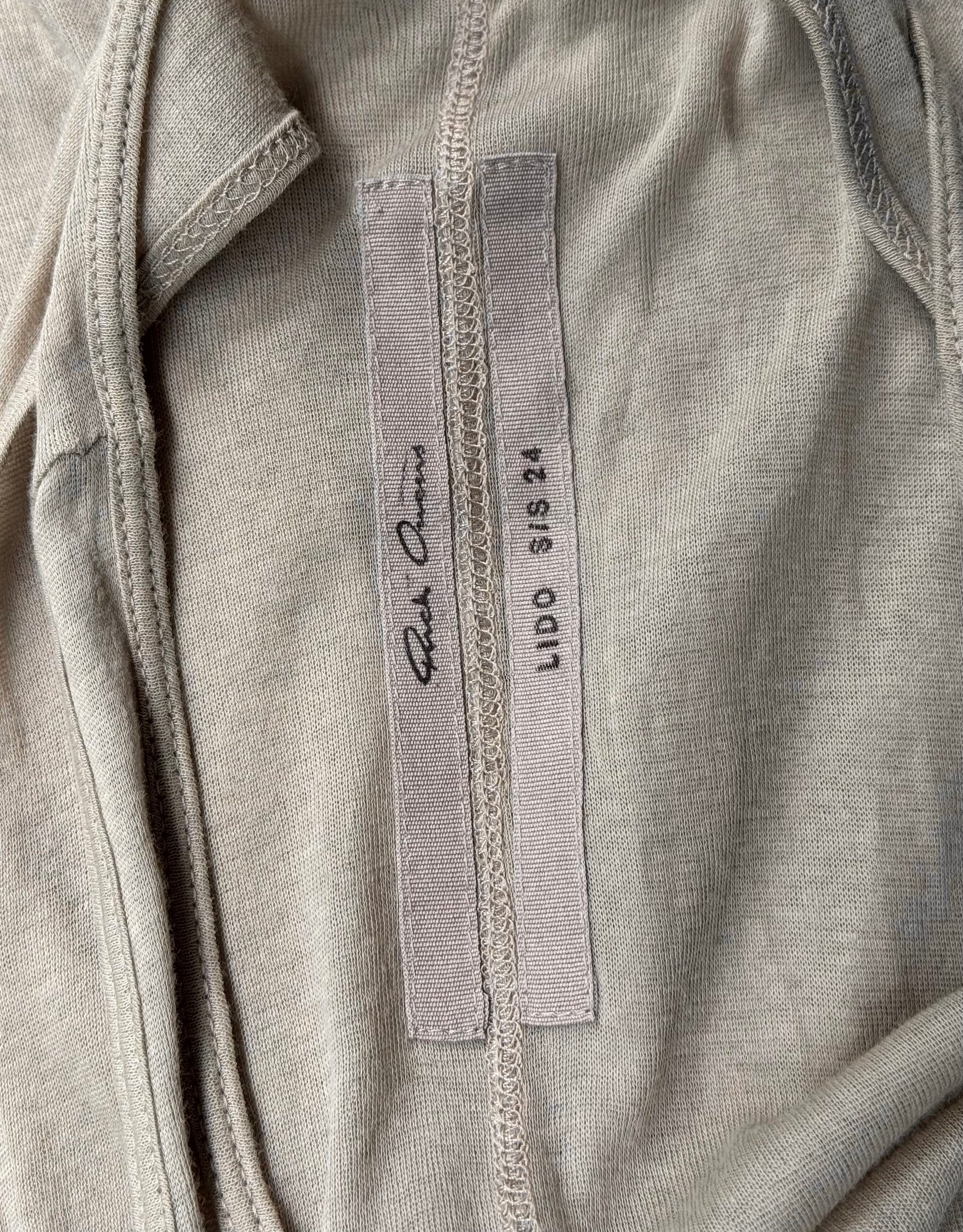 A pearl sheer tanks inner label features Rick Owens on one tag and LIDO SS24 with size SIS XS on the other, sewn onto the fabric—a subtle nod to avant-garde fashion’s attention to detail.