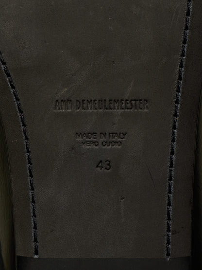 Close-up of the insole of a dark brown leather shoe, showing the embossed brand name 'Ann Demeulemeester', 'Made in Italy Vero Cuore', size '43', and decorative contrast stitching.