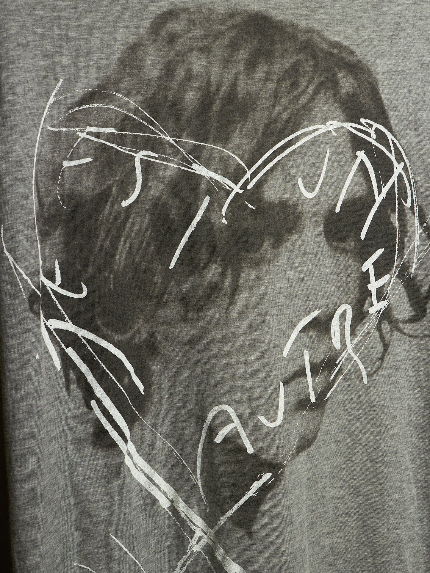Close-up of a gray heather graphic print featuring a dark, sketchy portrait with white scribbled text and lines overlaid across the face.