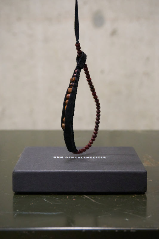 Bracelet with beads on a black stand against a neutral background