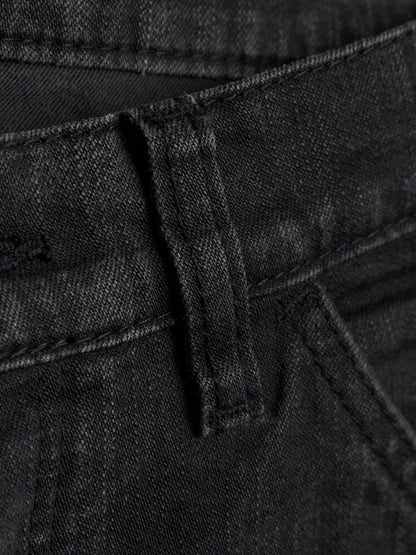 Close-up detail of black denim jeans showing the belt loop, waistband stitching, and fabric texture.