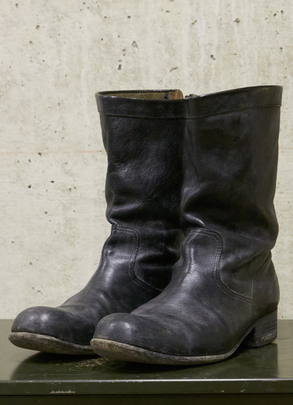 Pair of black leather boots on a textured surface with a neutral background