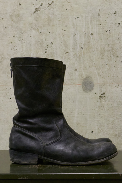 Black leather boot on a textured surface