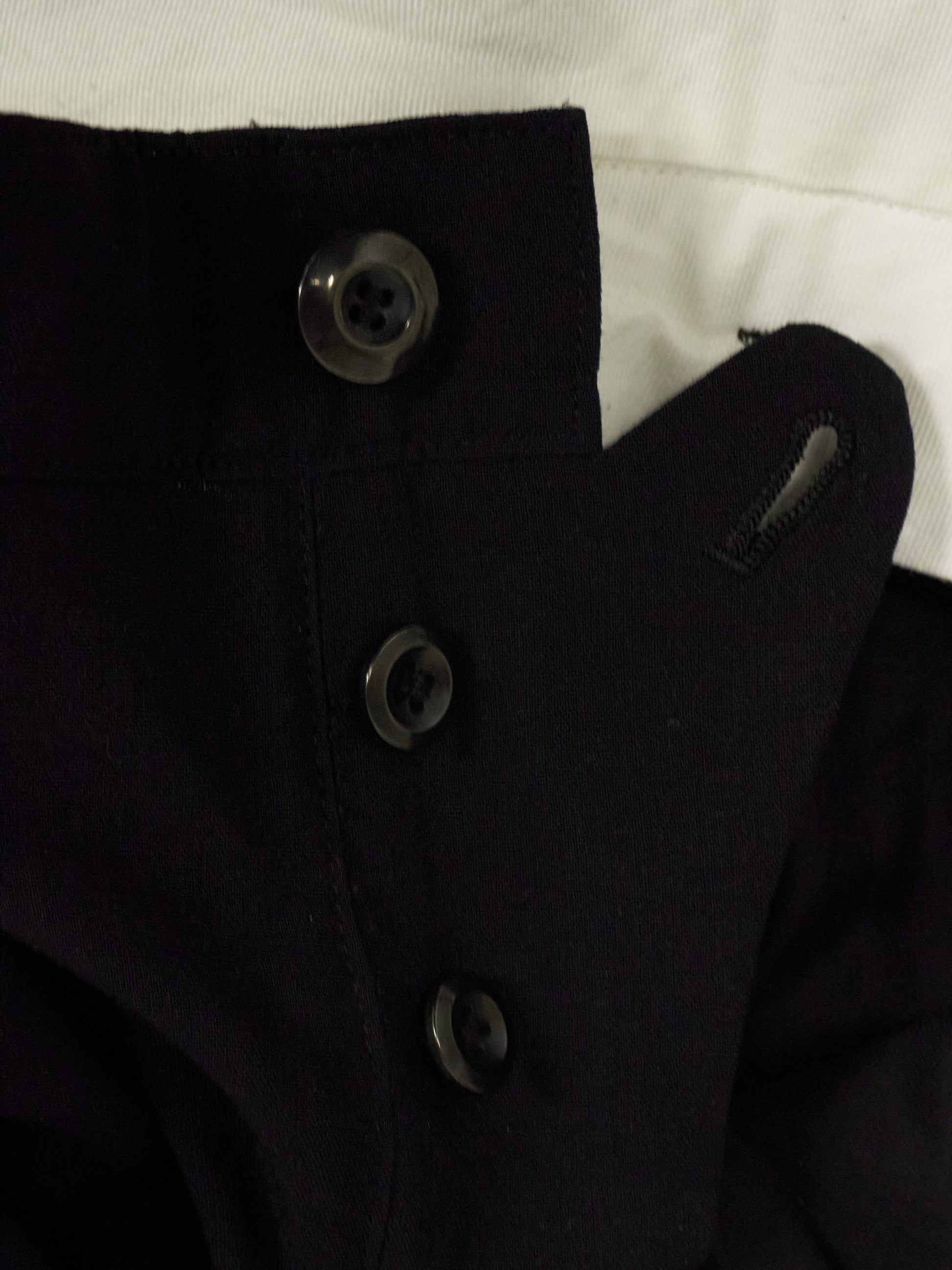 Close-up of a black coat with buttons on a white background