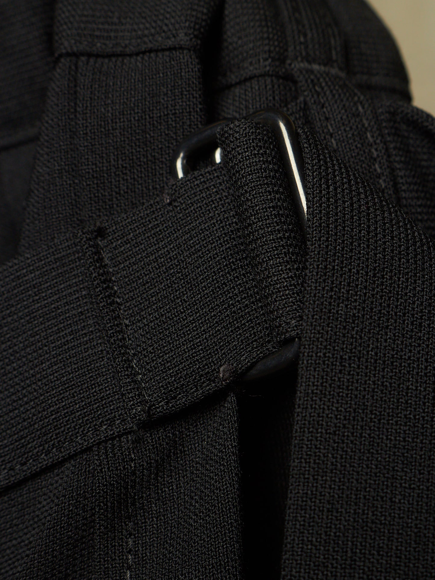 Close-up detail of a black woven fabric strap with a silver metal D-ring attachment.