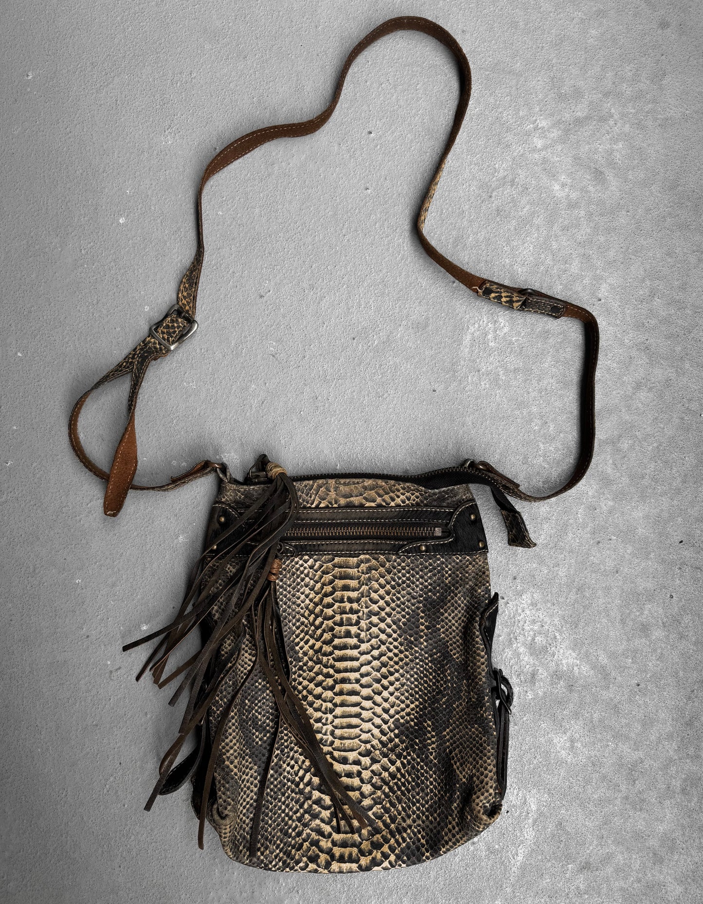 A Kyoji Maruyama Early 00s Yellow Crocodile Embossed Leather Side Bag with a long, adjustable strap and front zipper pocket rests on a gray textured surface. This Japanese designer bag features decorative leather fringes.