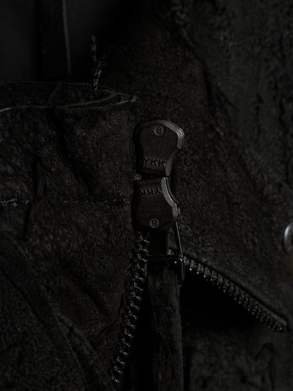Close-up of a black textured jacket with a black metal zipper featuring the brand name 'YKK' on the pull tab.