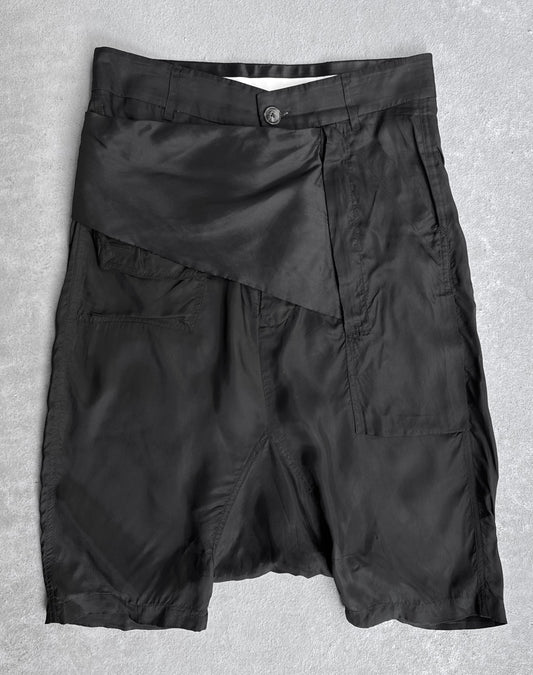 Rick Owens SS14 “VICIOUS” Lightweight Memphis Shorts in black, knee-length, with shiny asymmetrical flap and single button closure. Tagged IT40 (fits US 28-29). Flawless condition. Laid flat on light gray surface.