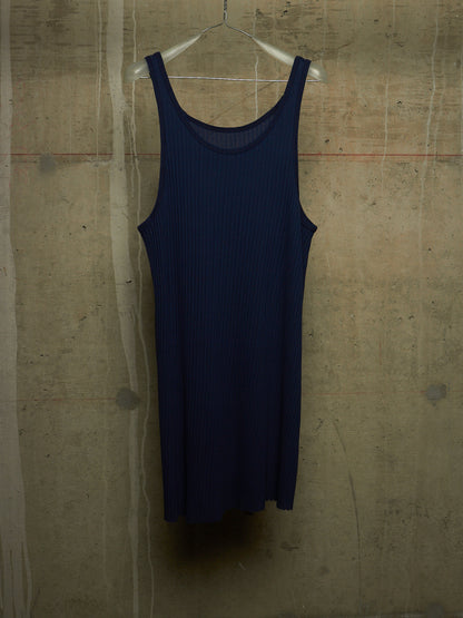 A dark navy blue ribbed knit tank dress hanging on a clear plastic hanger against a textured concrete wall.