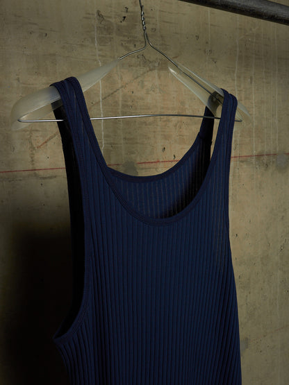 A dark navy blue ribbed tank top hanging on a clear plastic hanger against a textured concrete wall.