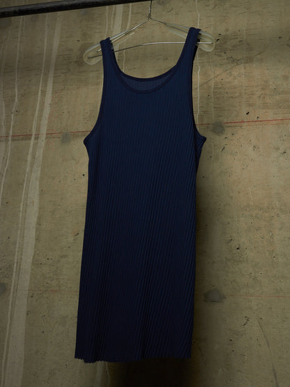 A dark navy blue ribbed knit tank dress hanging on a clear plastic hanger against a textured concrete wall.