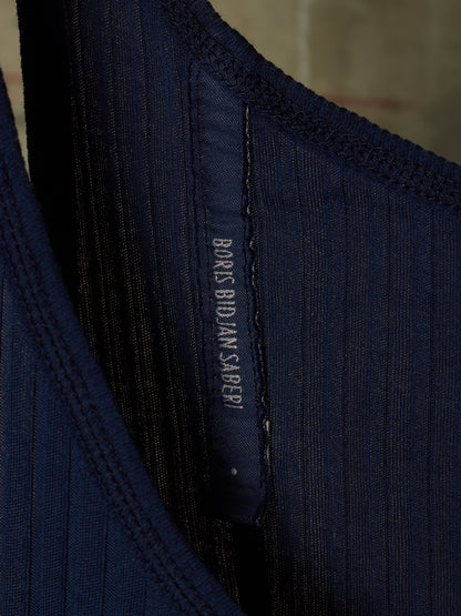 Close-up of a dark navy ribbed knit garment showing the inner neck lining and a sewn-in size label that reads BONES BIDS ANY SLEEPER.