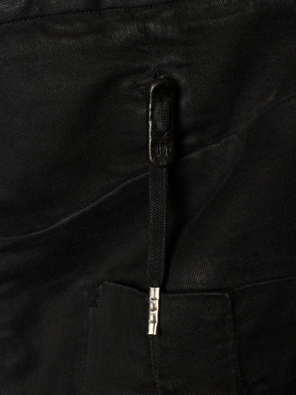 Close-up of a black fabric garment showing a black zipper pull with a silver metal accent and the embossed brand name 'SASAKI'.