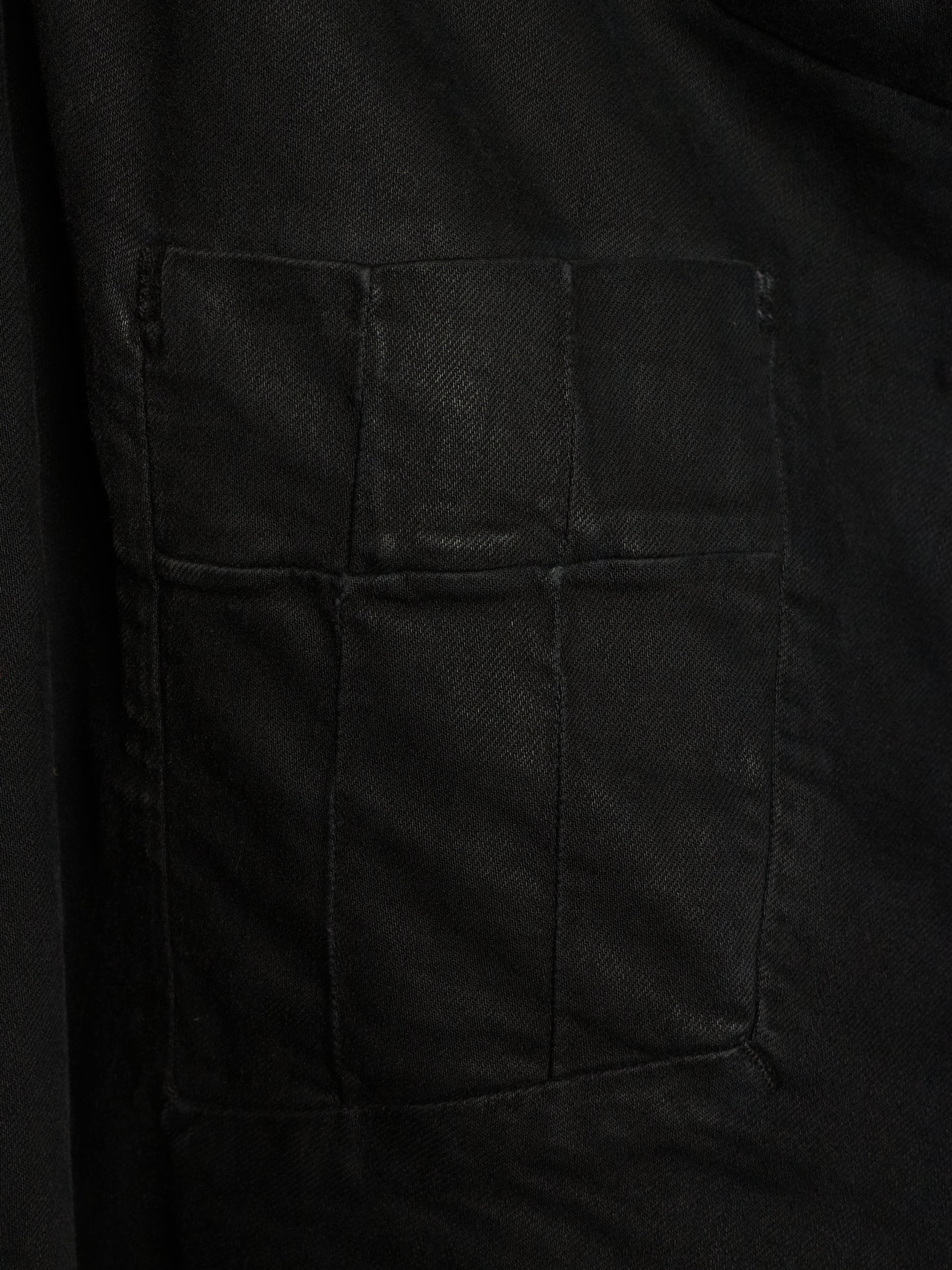Close-up of a black fabric garment showing a large rectangular patch pocket with stitched seams.