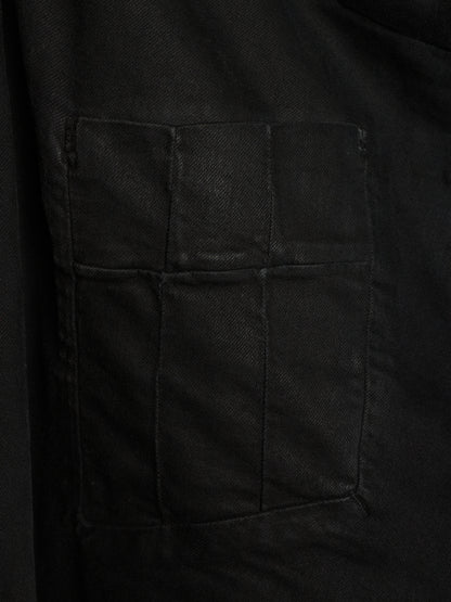 Close-up of a black fabric garment showing a large rectangular patch pocket with stitched seams.