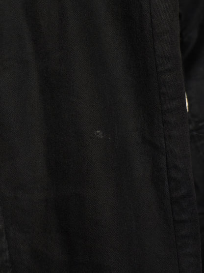 Close-up of a black textured fabric surface with a visible seam and a small light speck on the material.