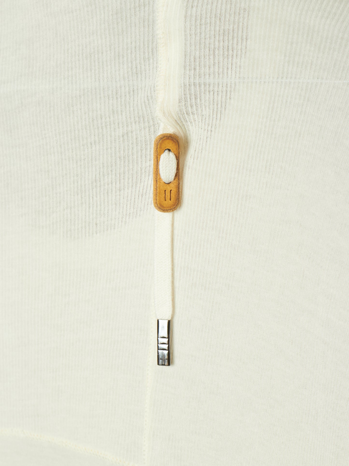 Close-up of a white textured knit garment featuring a white zipper with a light brown wooden pull tab and a silver metal tip.