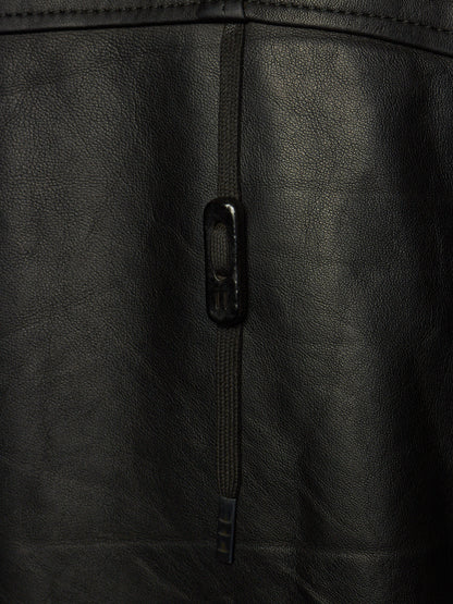 Close-up of a black leather jacket showing a vertical zipper with a black metal pull tab and the textured leather surface.