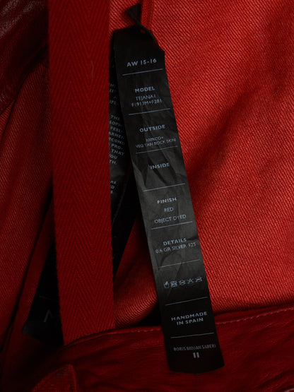 A close-up shot of a black hangtag attached to a red textured fabric garment, showing printed specifications on the tag.