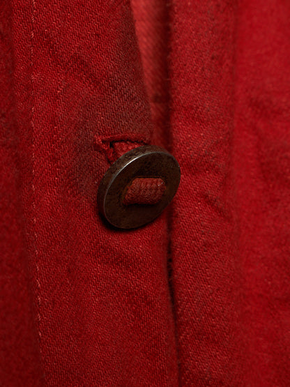 Close-up of a textured red fabric garment featuring a dark brown metal ring pull button.