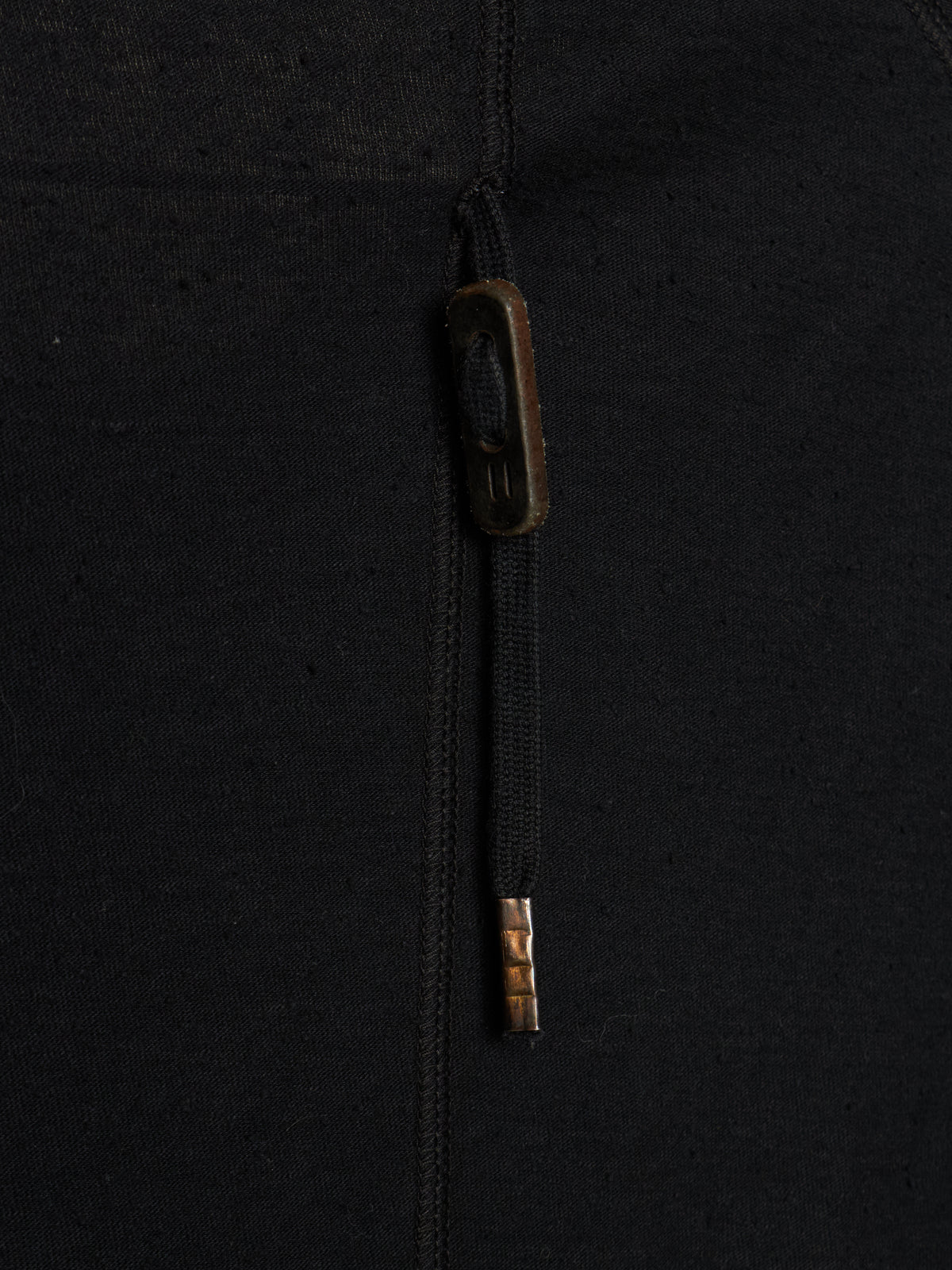 Close-up of a black zippered garment with a dark brown zipper pull tab and a small metallic gold accent near the bottom of the zipper pull.