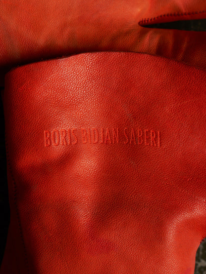 Close-up of a textured red leather or faux-leather surface with the debossed text 'BORIS SIDIAN SABERI' visible in the center.
