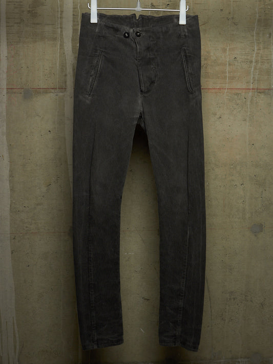 A pair of faded black denim jeans hanging from white plastic hangers against a textured concrete wall.