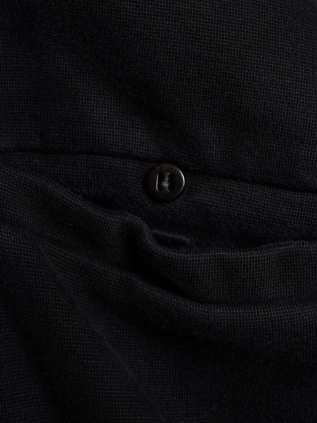Close-up of a black textured knit garment with a small dark button detail.