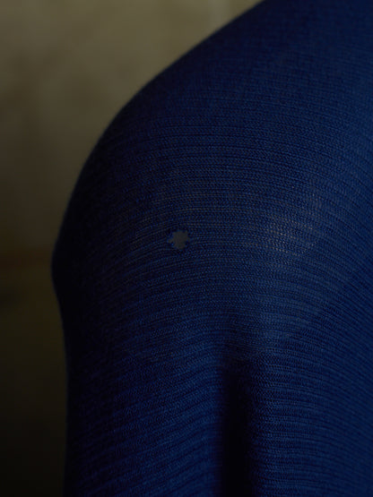 Close-up of a dark blue ribbed knit fabric with a small light-colored star-shaped defect or stain near the center.