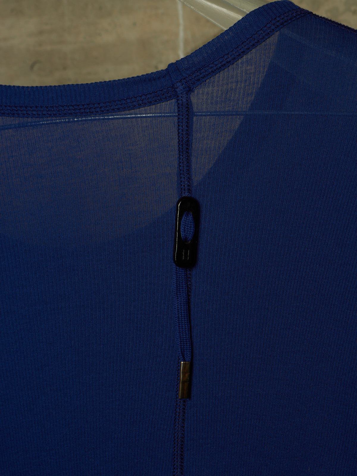 Close-up of a royal blue athletic top showing the back neckline, mesh fabric, and a black hook-and-loop closure.