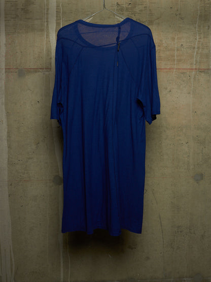 A royal blue short-sleeve dress hanging on a wire hanger against a textured concrete wall.
