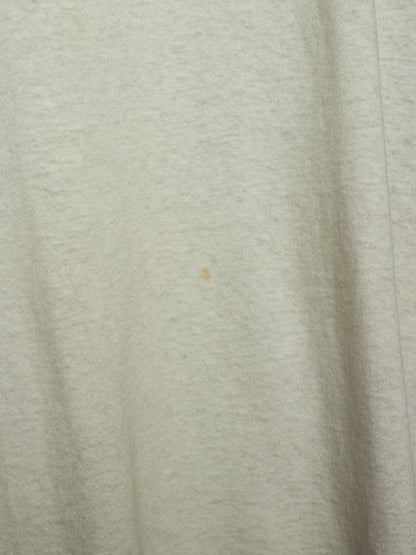 A close-up of a light heather gray fabric surface with soft folds and a tiny small brown speck near the center.
