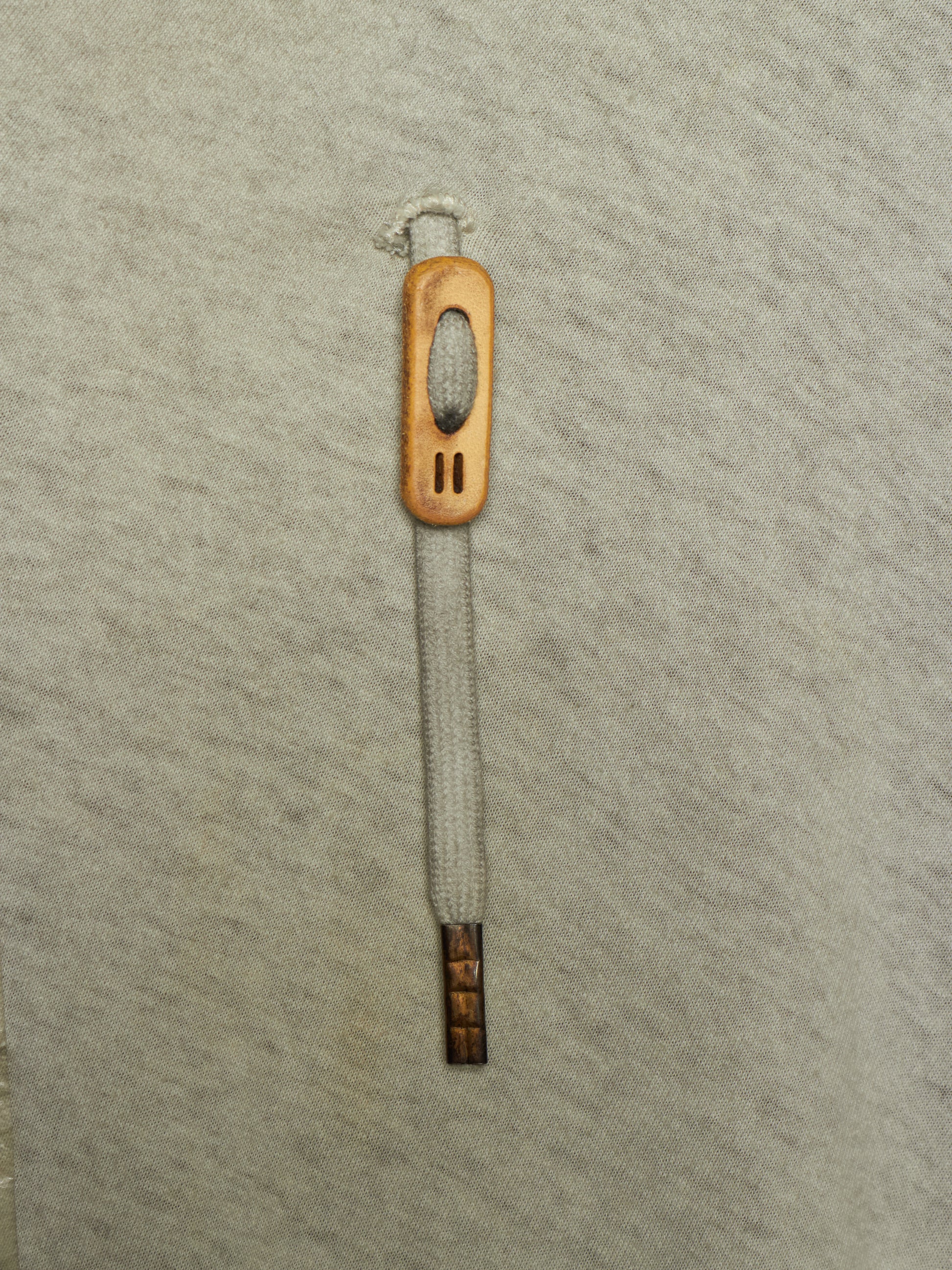 A single wooden shoe pull tab with a light gray woven rope handle, shown vertically on a textured light gray background.