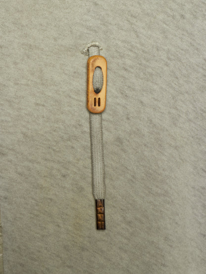 A single wooden shoe pull tab with a light gray woven rope handle, shown vertically on a textured light gray background.