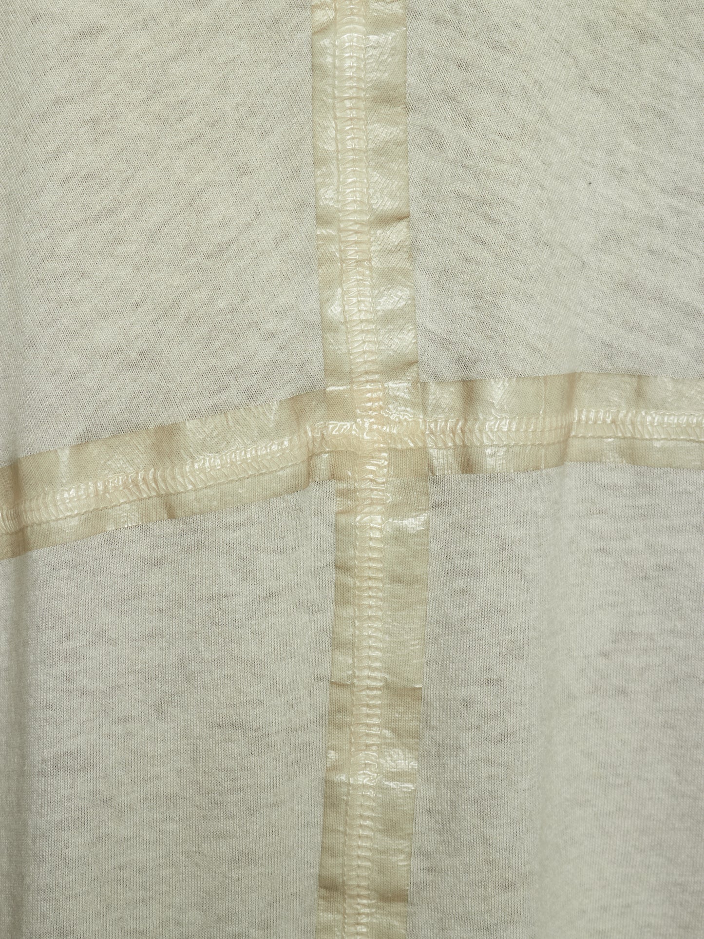 Close-up of a light heather gray fabric with a cream-colored satin cross seam or trim intersecting at the center.