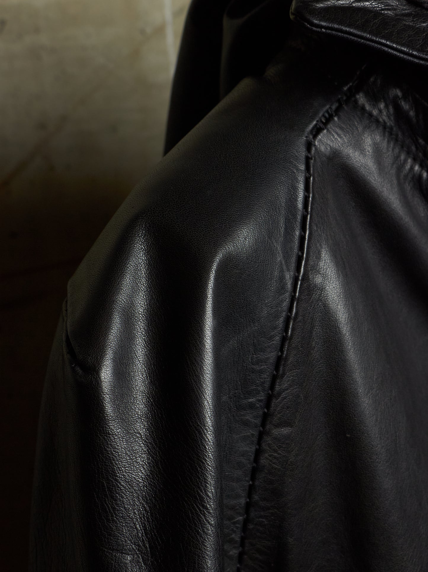 Close-up of a black leather jacket showing the texture of the leather and a visible seam.