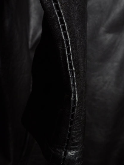 Close-up of a black leather garment, showing a seam with double stitching on a dark background.