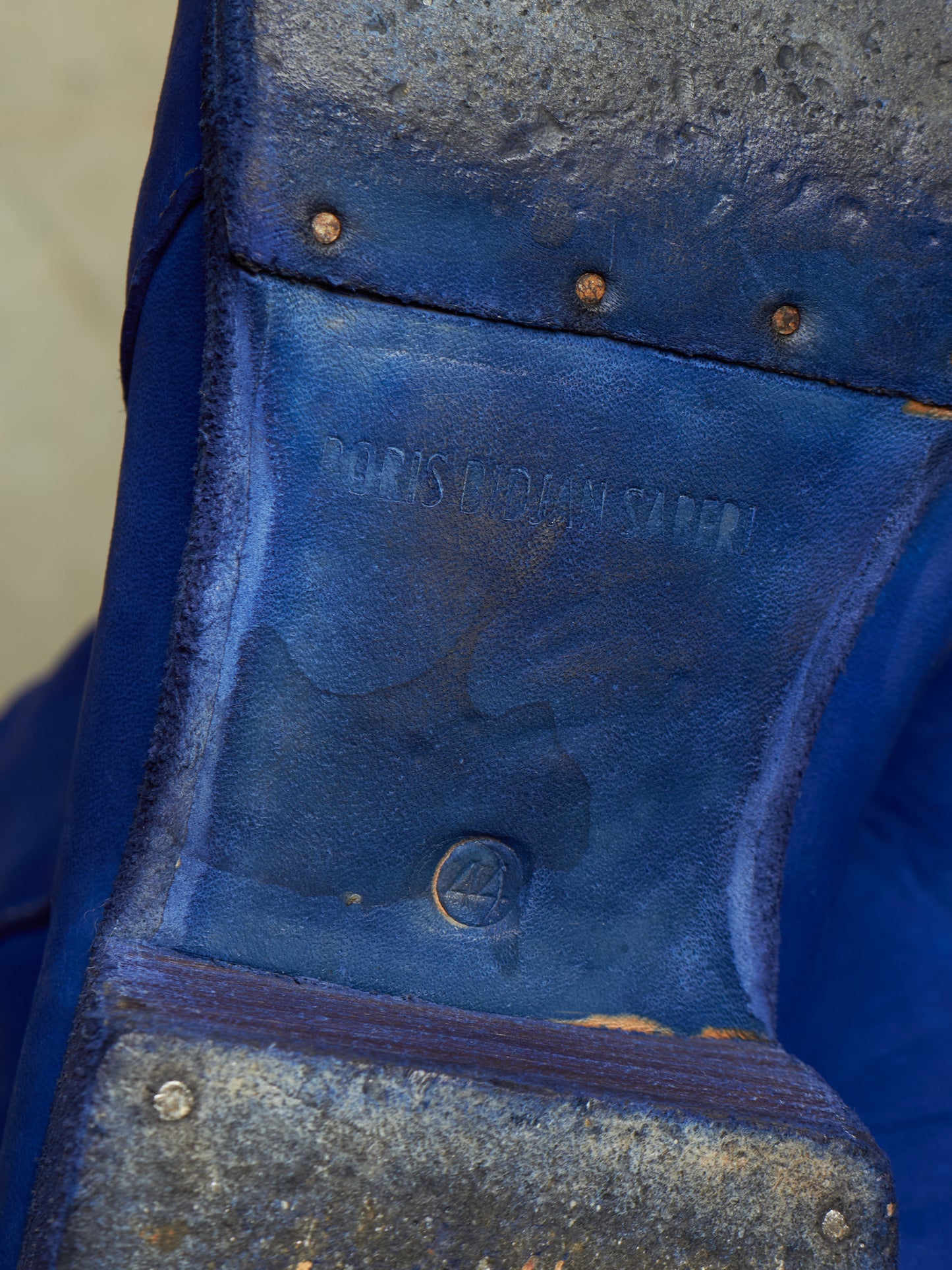 Close-up of the sole of a blue leather shoe, showing the brand name 'PORIS KUHNMANN' molded into the leather, along with rivets and a metal outsole.