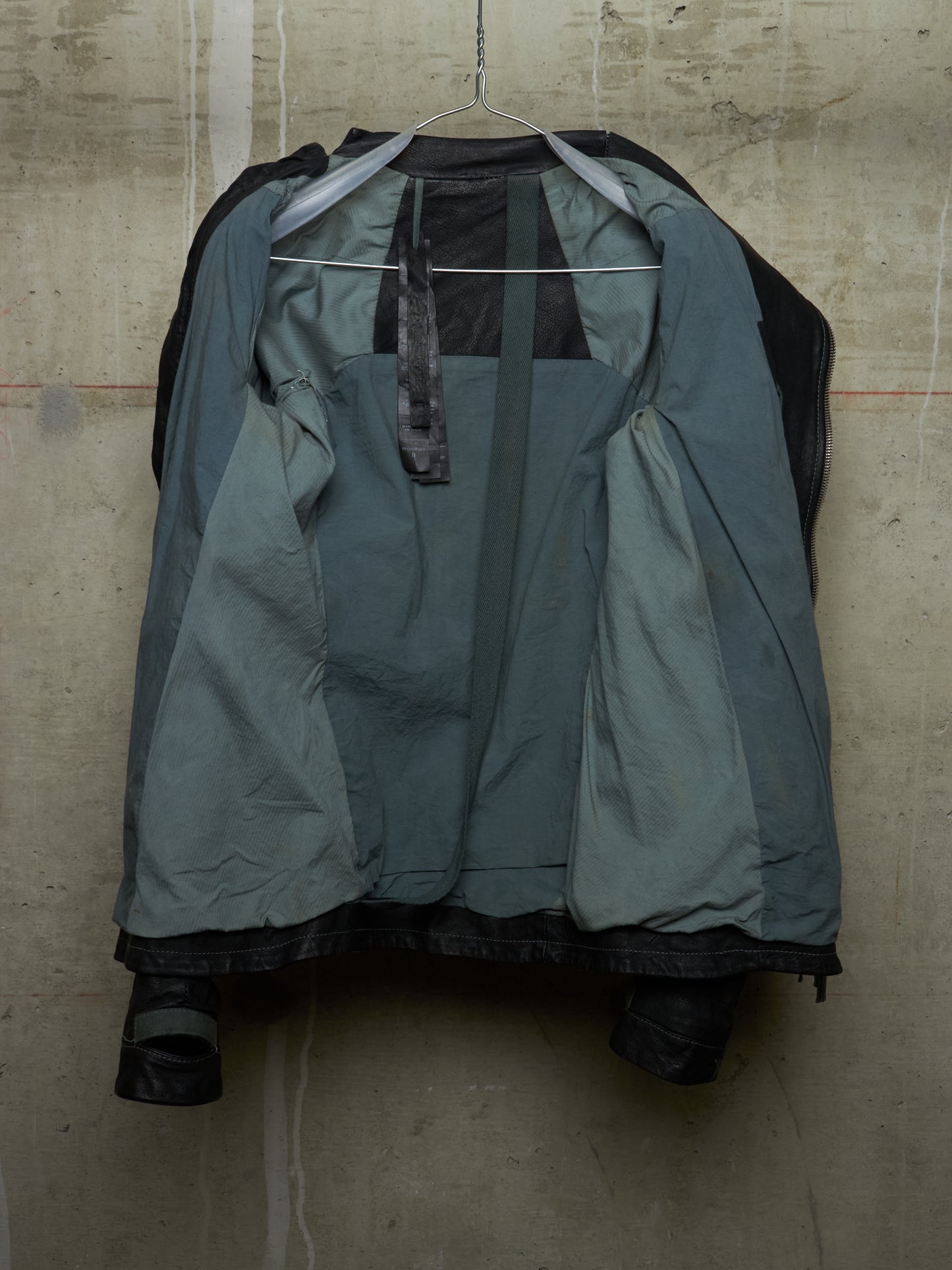 Green raincoat on a hanger against a textured wall
