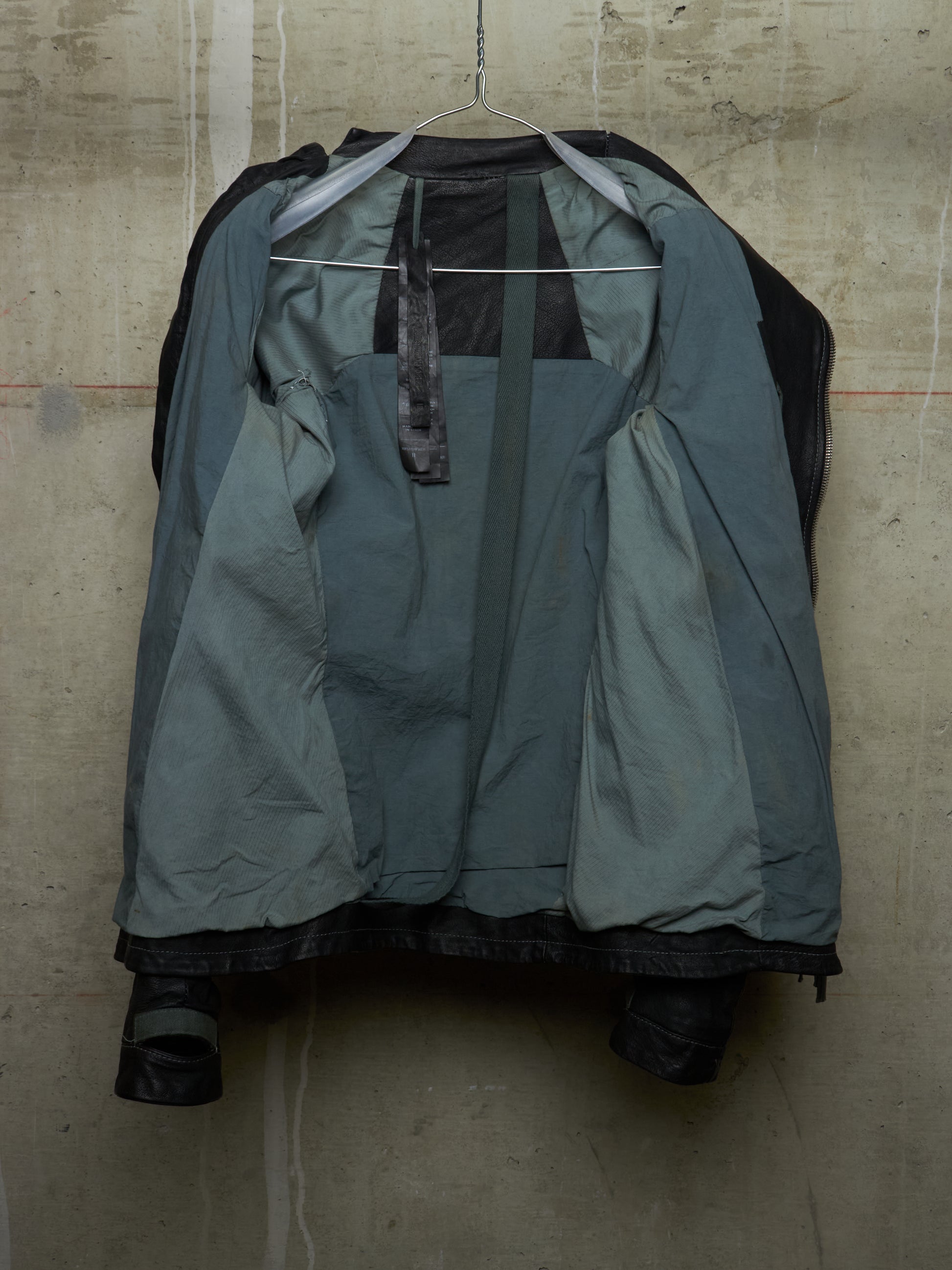 Green raincoat on a hanger against a textured wall