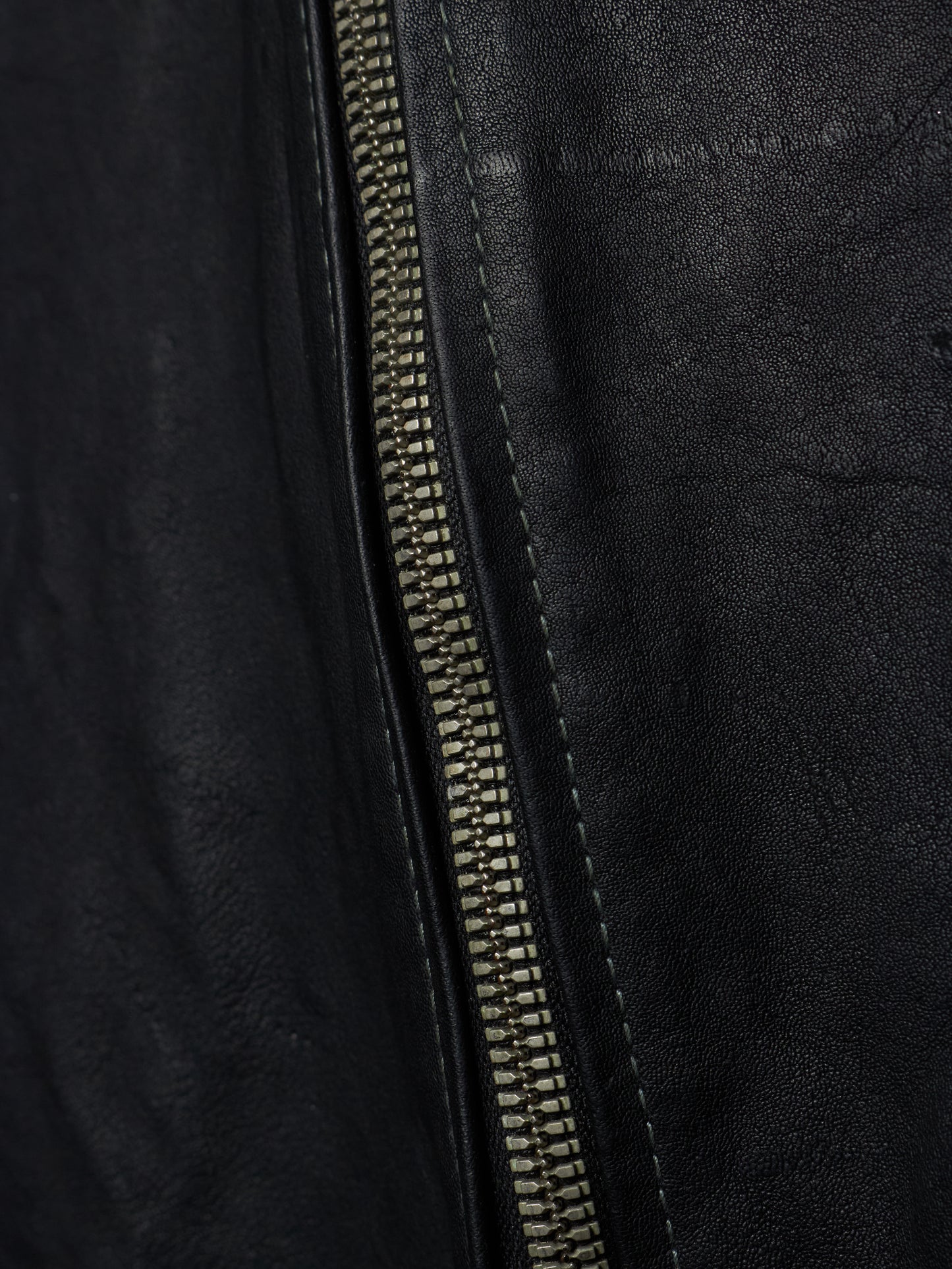 Close-up of a black leather jacket with a zipper