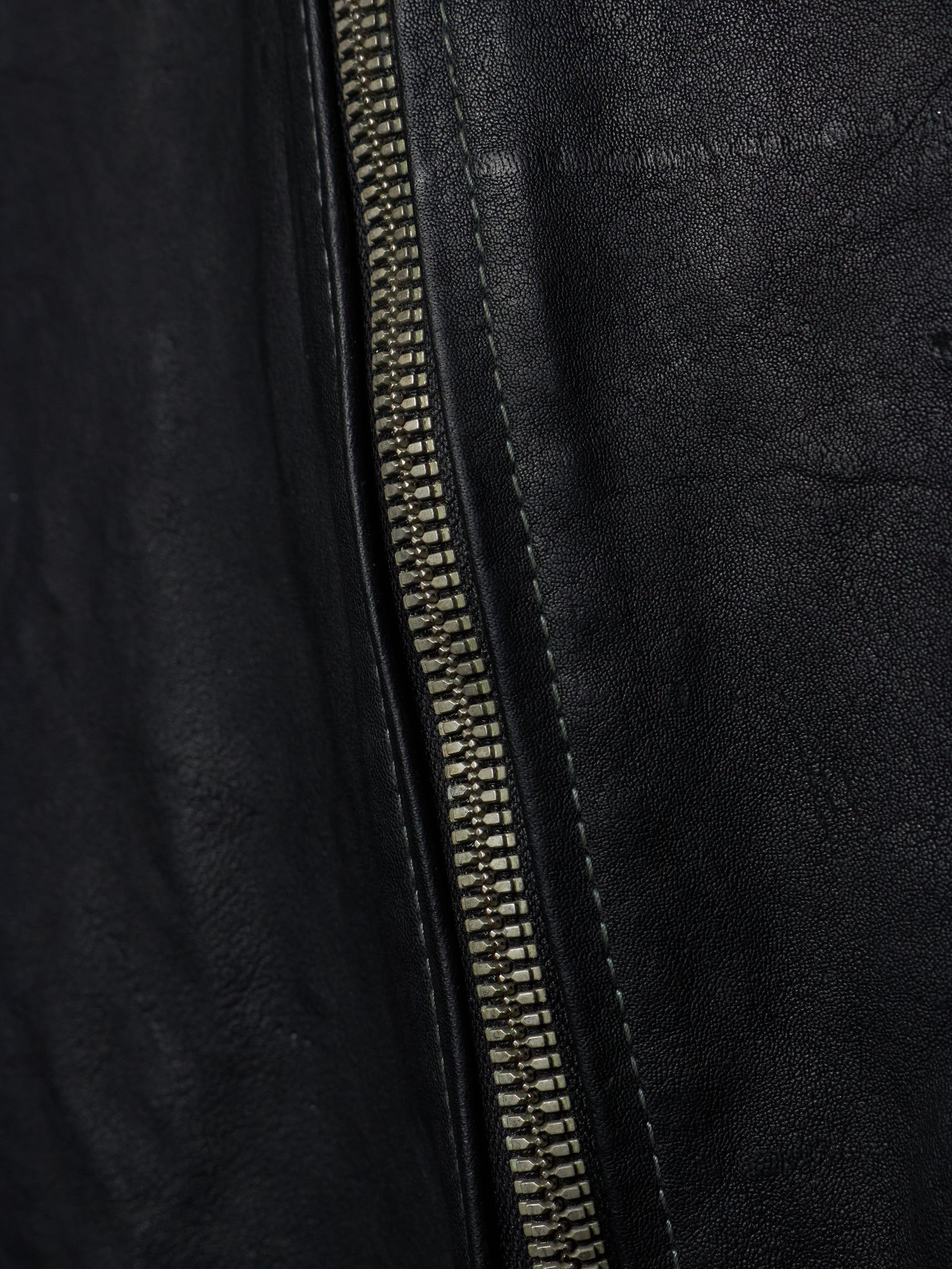 Close-up of a black leather jacket with a zipper