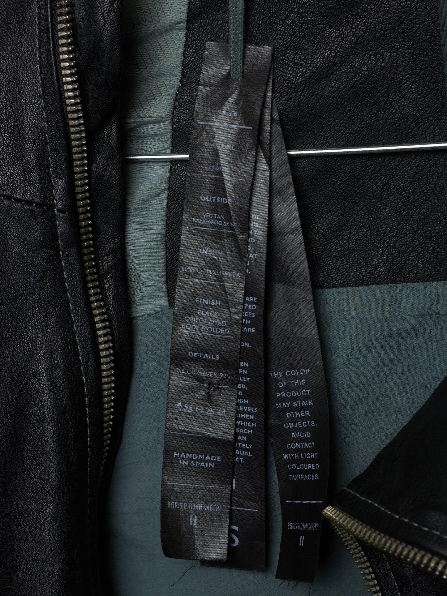 Close-up of a black leather jacket with a brand label on a dark background