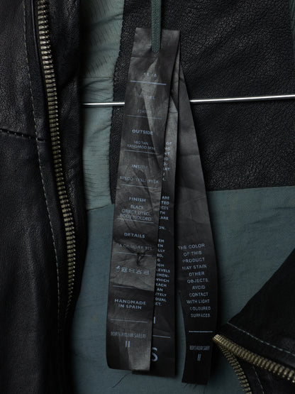 Close-up of a black leather jacket with a brand label on a dark background