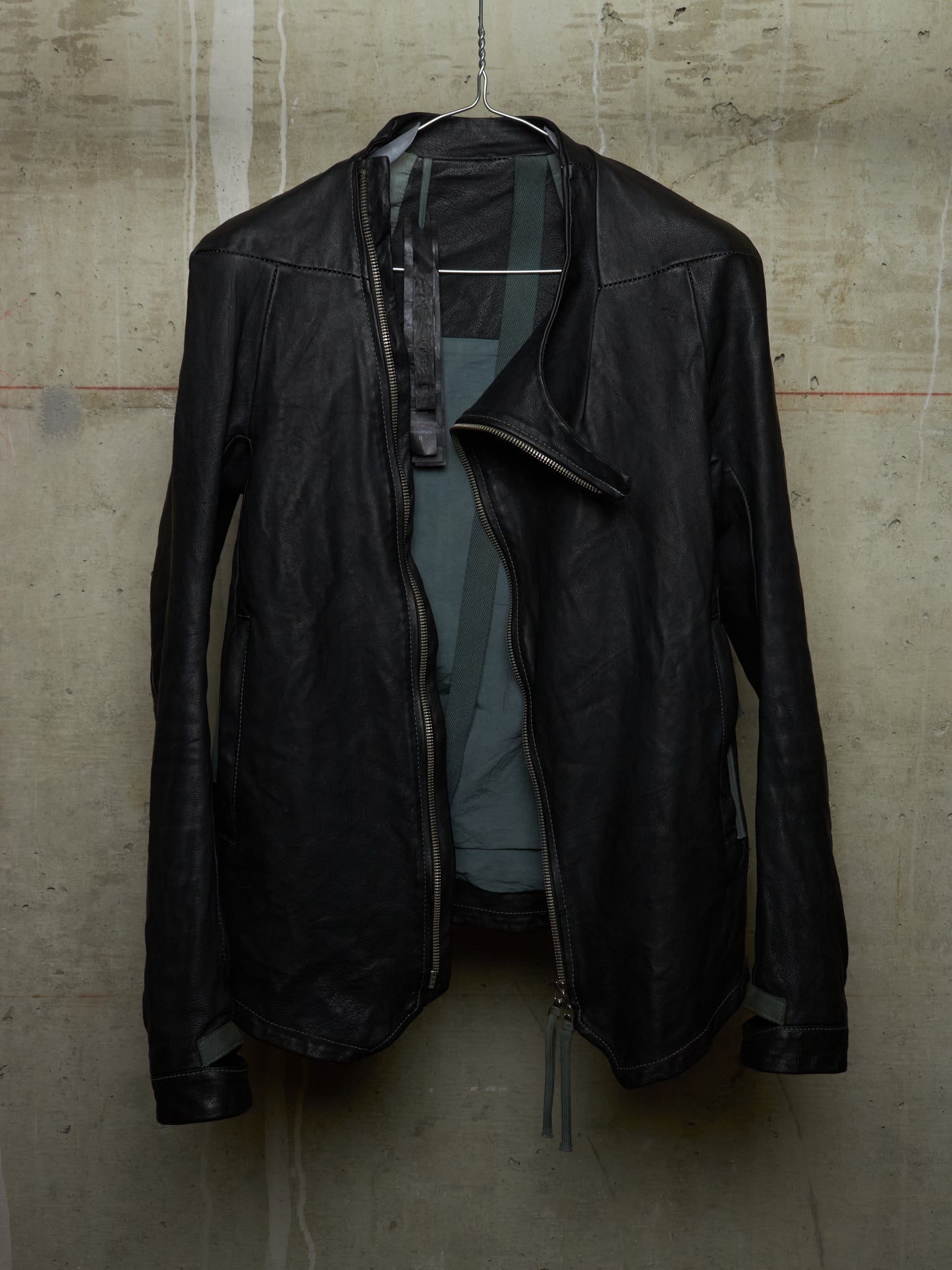 Black leather jacket hanging on a textured wall
