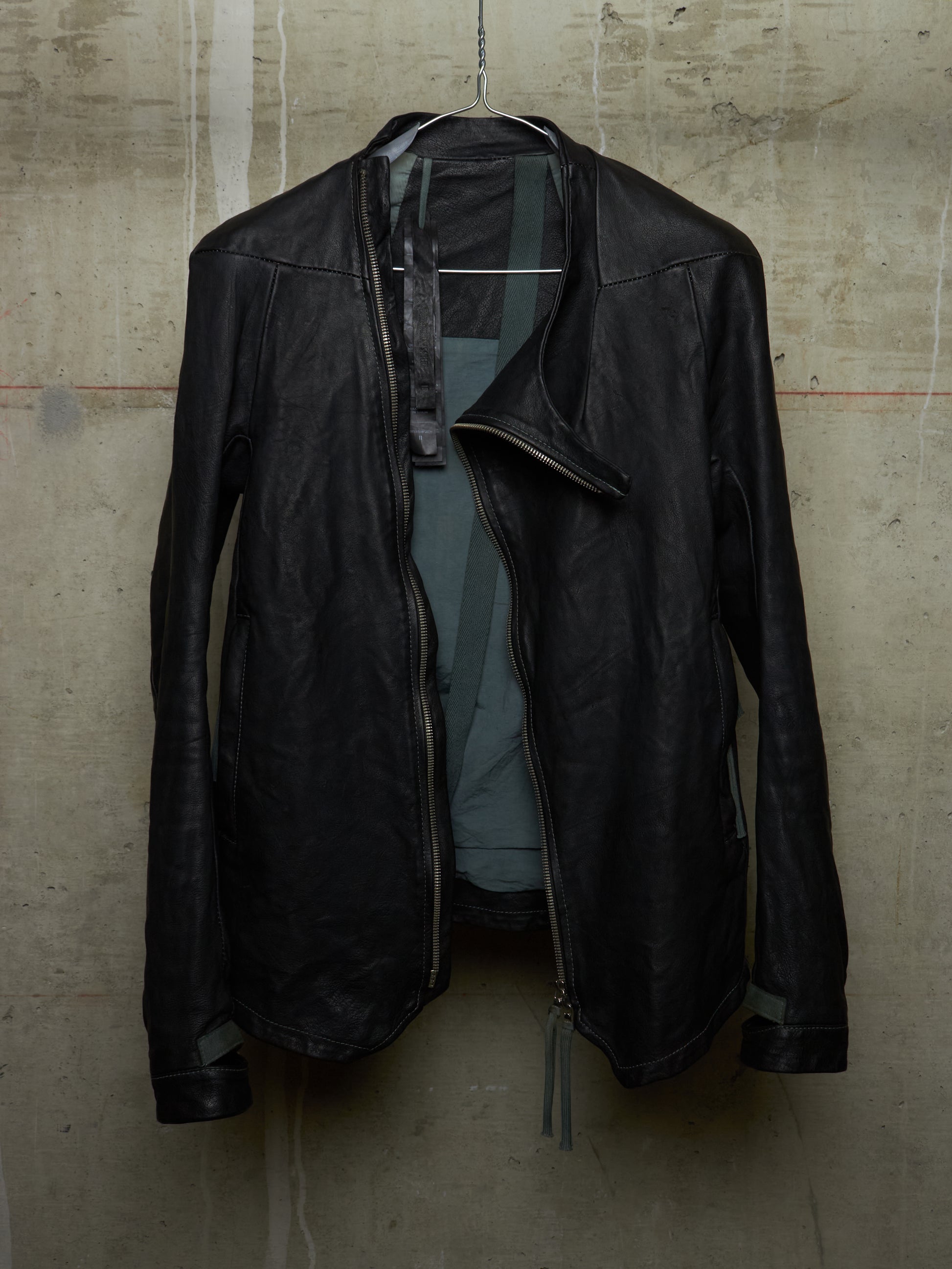 Black leather jacket hanging on a textured wall