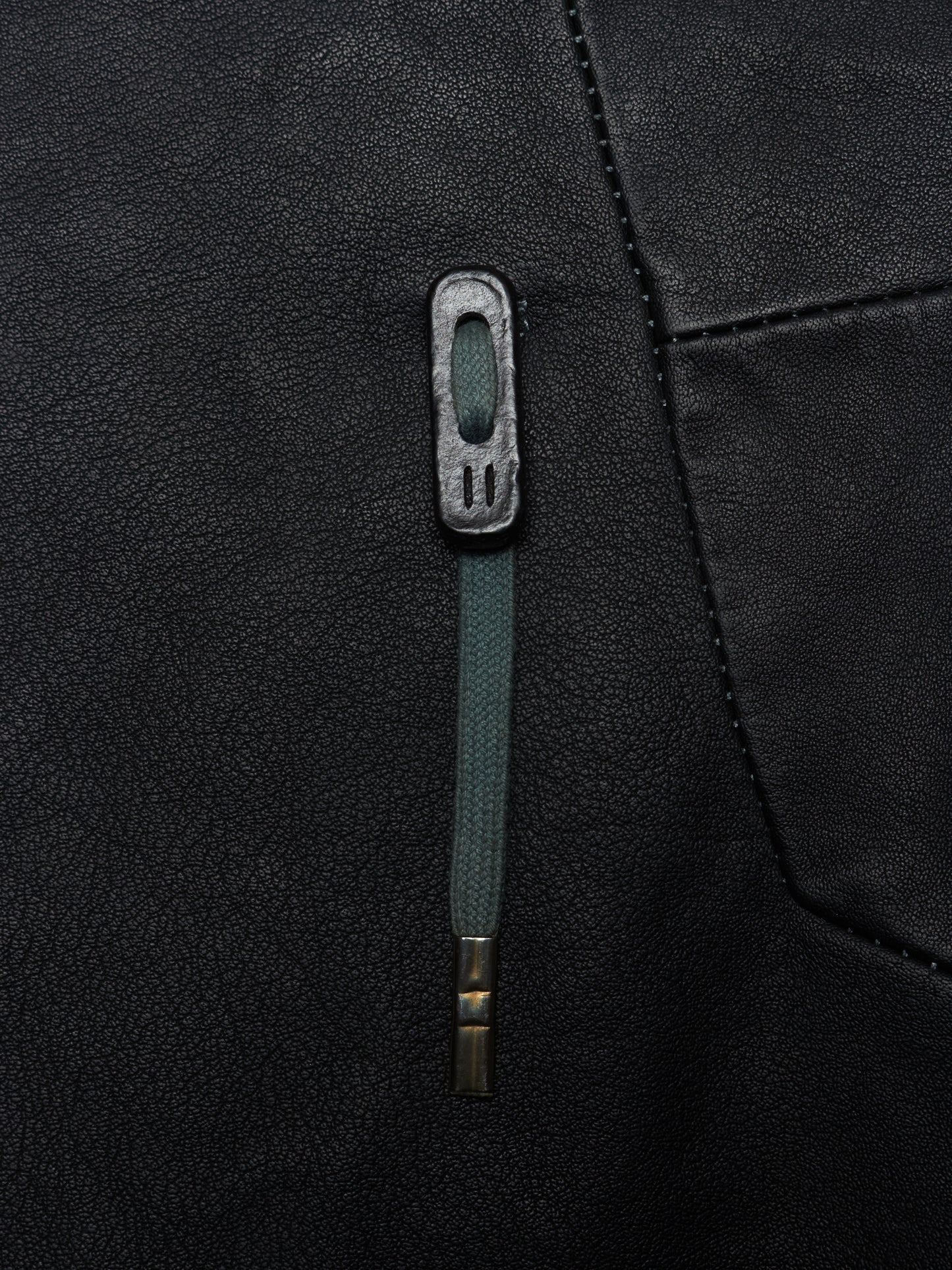 Close-up of a black jacket with a green zipper and button detail.