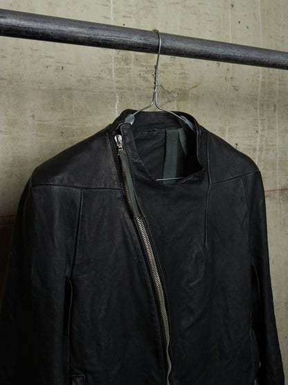 Black jacket hanging on a metal rod against a textured wall.