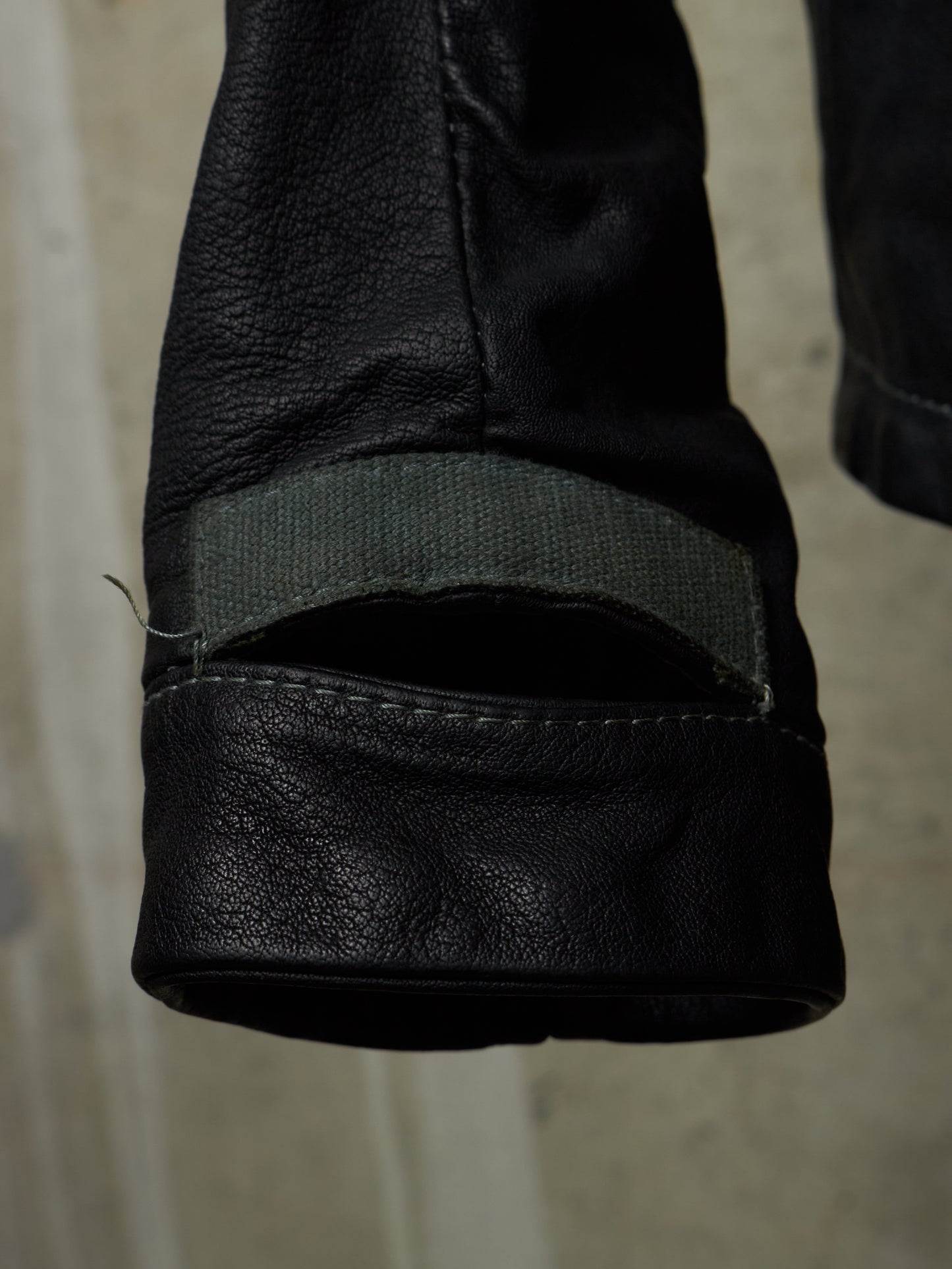 Close-up of a black leather boot with a visible stitching detail on a neutral background
