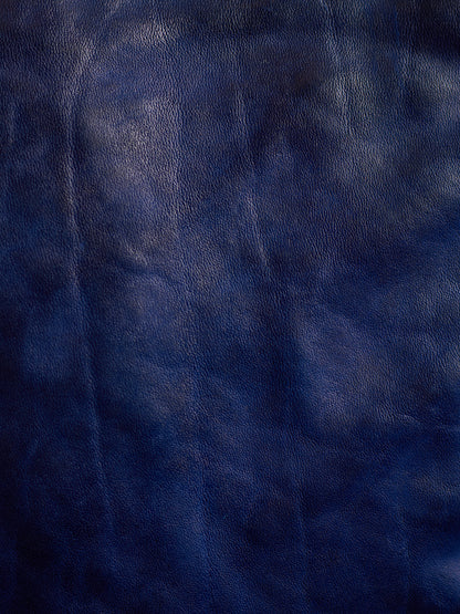 A close-up of dark navy blue textured material, resembling leather or faux leather with subtle sheen and grain.